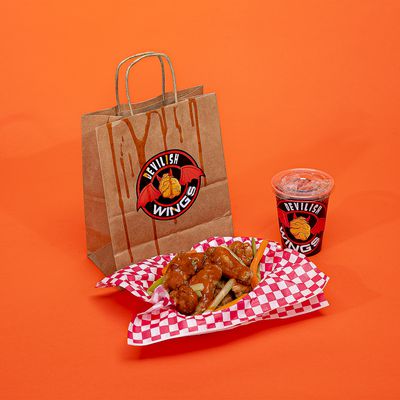 A bag with a sticker for a fake brand called Devilish Wings next to a basket of chicken wings and a clear plastic cup with another sticker for Devilish Wings on an orange backdrop.