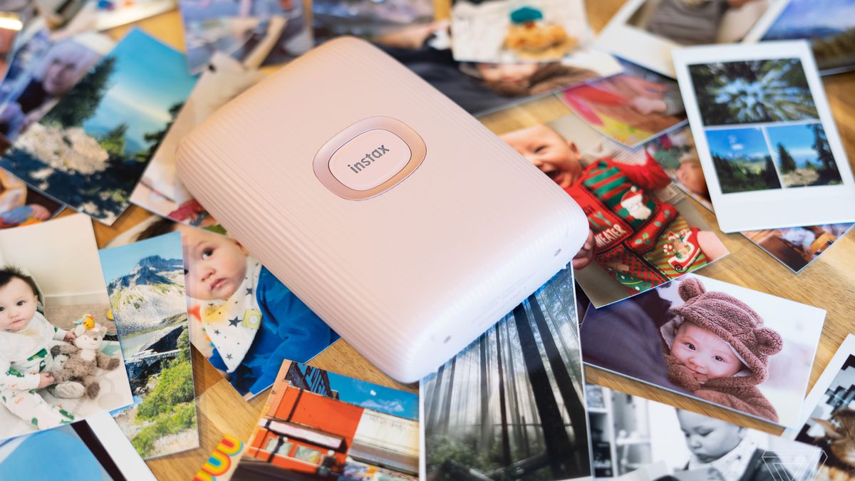 Instax Mini Link 2 on a backdrop of printed photos.