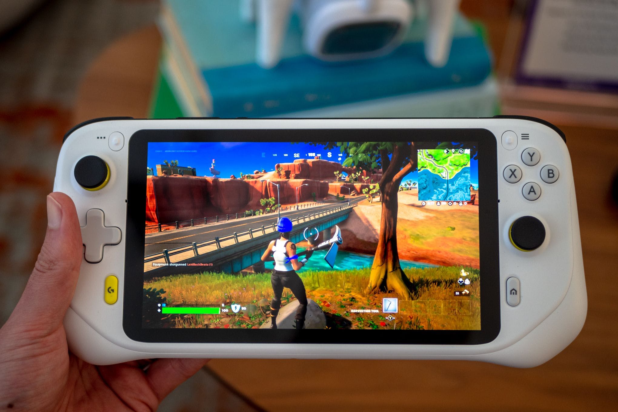 Holding Logitech’s G Cloud Gaming Handheld in one hand. It’s displaying the game Fortnite, wherein a character is staring off a cliff into the horizon.