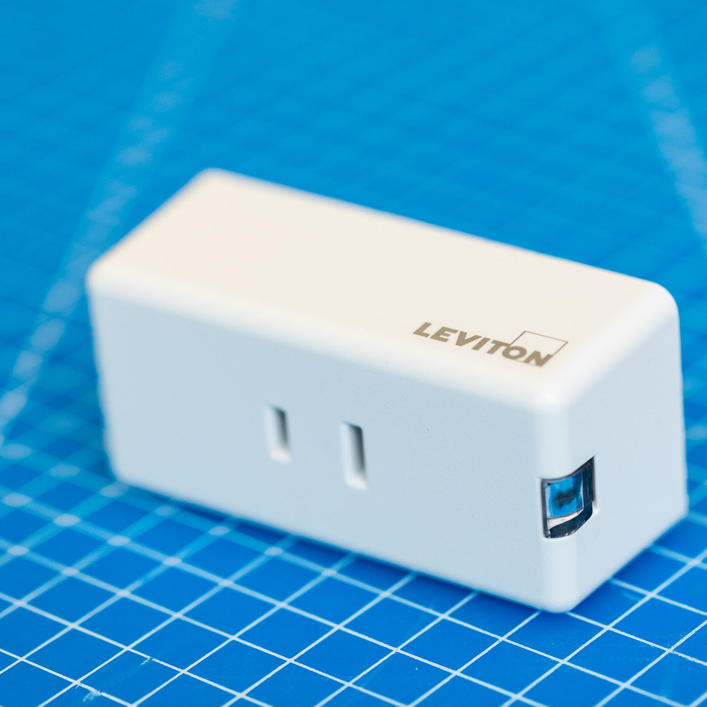 The Leviton smart dimmer, a white rectangular prism with a two-prong US-style AC outlet on the front.